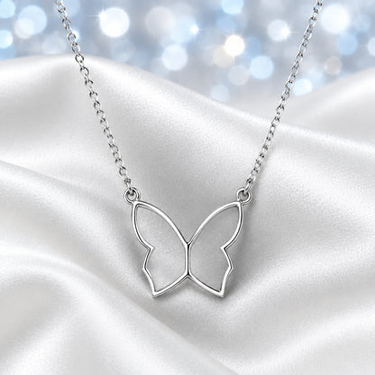 A delicate silver butterfly pendant necklace on a fine link chain, displayed on a draped white satin fabric background.