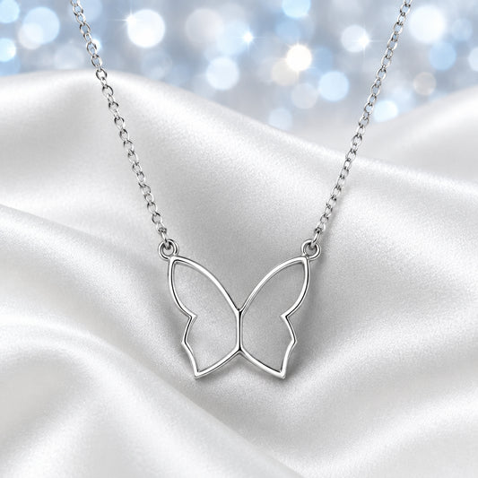 A delicate silver butterfly pendant necklace on a fine link chain, displayed on a draped white satin fabric background.