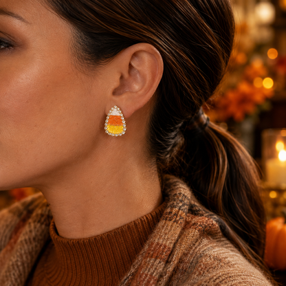 A close-up of a woman wearing a Candy Corn Rhinestone Earrings, set with small clear stones and gold-toned metal.