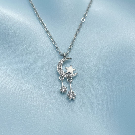 Silver Celestial Moon & Star Dangle Necklace on a light gray background