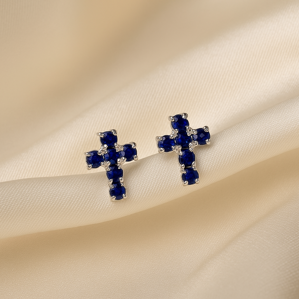 Silver Mini Blue Crystal Cross Earrings with blue gemstones on a beige fabric background