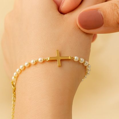 Gold Cross Pearl Bracelet/Anklet on a wrist against a beige background