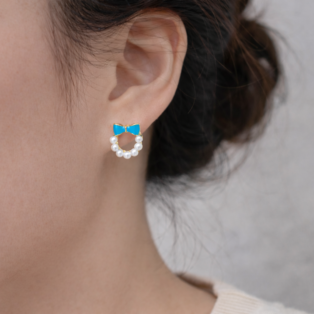 Blue Bow Pearl Wreath Earrings on an ear against a neutral background