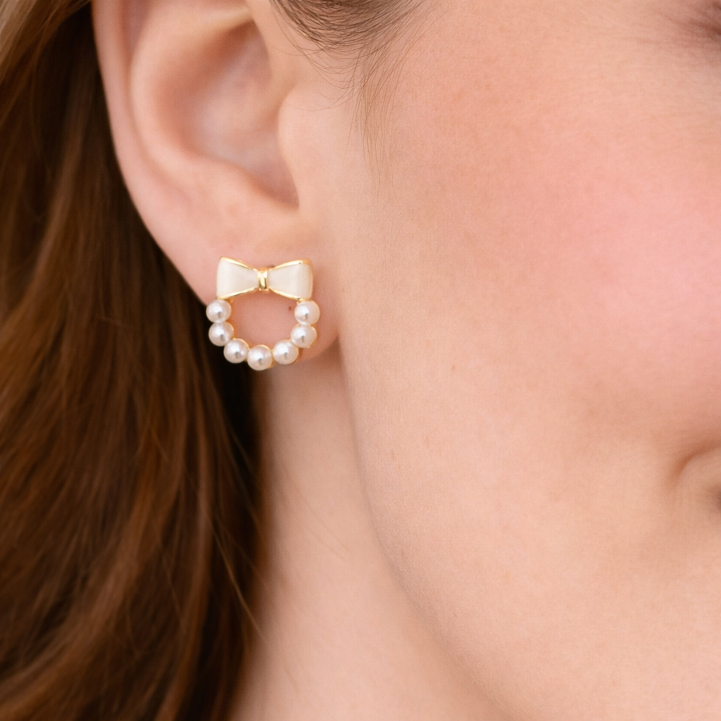 Pearl and gold bow earringIvory Bow Pearl Wreath Earring person with brown hair.