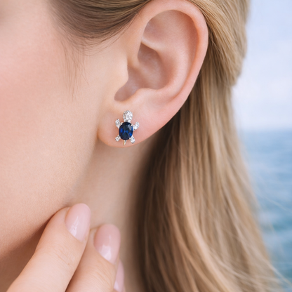 Close-up of an ear wearing a Blue Crystal Turtle Earring with a blurred background