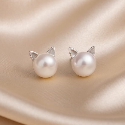 Pearl cat earrings on a beige fabric background