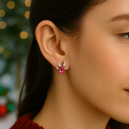 Close-up of a woman wearing Crystal Pink Reindeer Earrings with antlers against a blurred festive background.