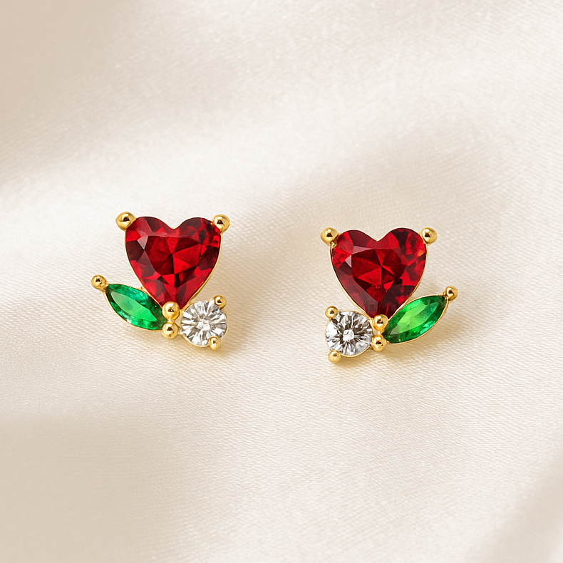 Mini Ruby Heart Blossom Earrings with red, green, and clear stones on a beige background