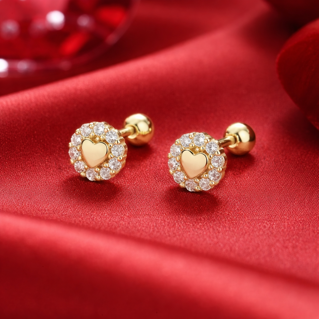 Tiny Gold Heart Halo Earrings with diamond accents on a red fabric background