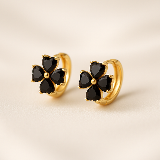 Black Flower Petal Hoop Earrings with black gemstones on a beige background