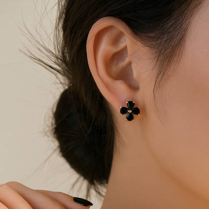 Close-up of a person wearing Black Flower Petal Hoop Earrings with a blurred background.