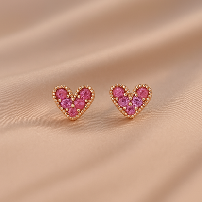 Petite Pink Zircon Heart Earrings with pink gemstones on a beige fabric background