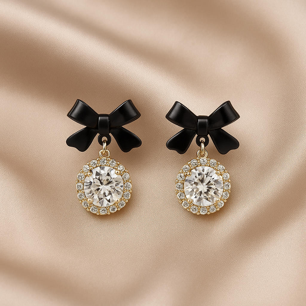 Pair of Black Bow Crystal Drop Earrings on a beige fabric background