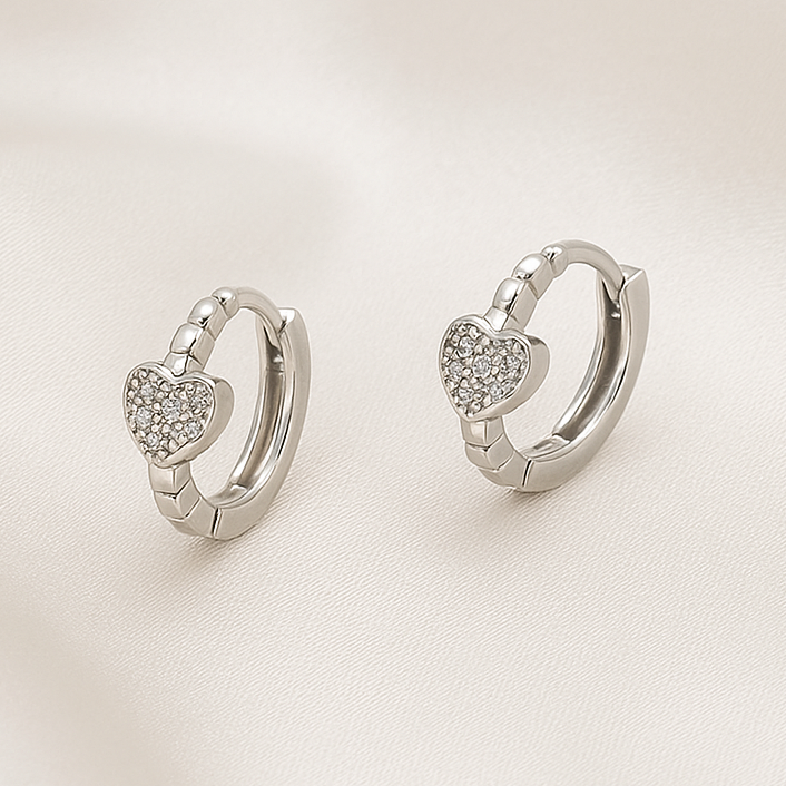 Pair of Silver Tiny Crystal Heart Earrings on a light background