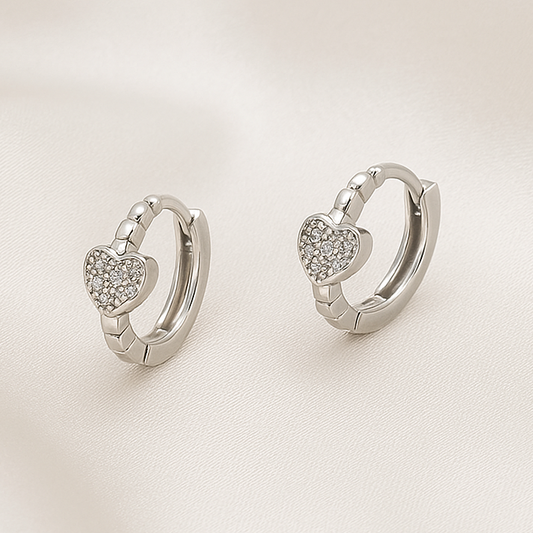 Pair of Silver Tiny Crystal Heart Earrings on a light background