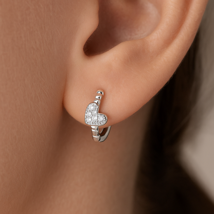 Silver Tiny Crystal Heart Earrings worn on an ear with a neutral background