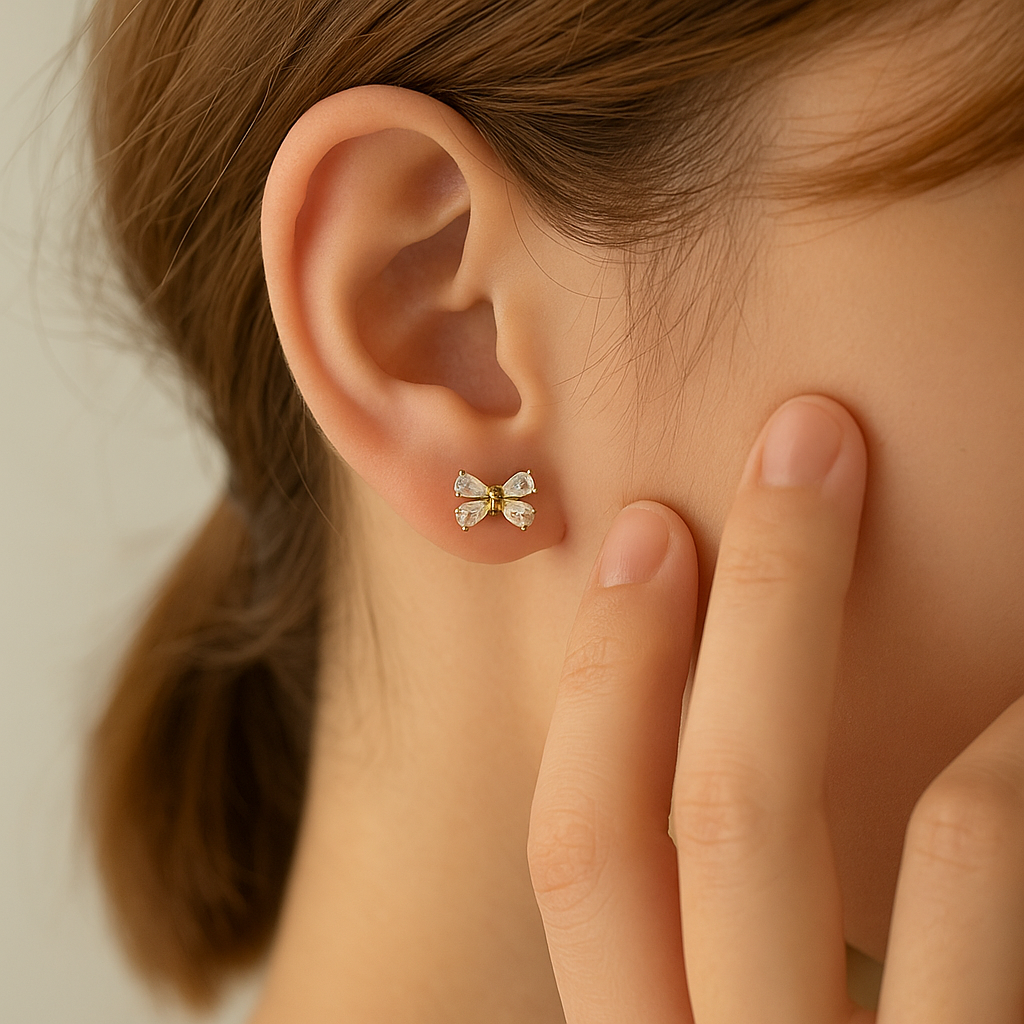 Close-up of an ear wearing Mini Crystal Bow Earrings with a blurred background