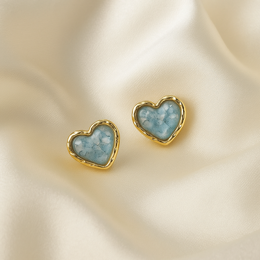 Aqua Blue Opalescent & Gold Heart Earrings on a beige fabric background