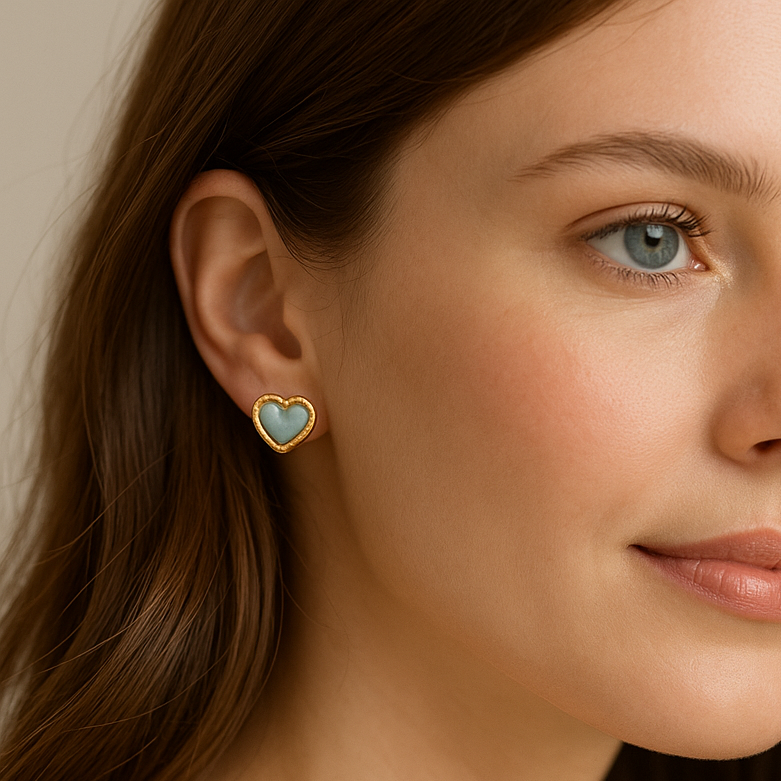 Close-up of a woman wearing Aqua Blue Opalescent & Gold Heart Earrings with a neutral background