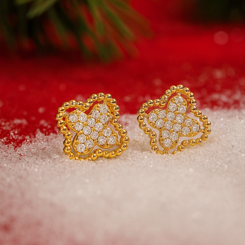 Gold Rhinestone Clover Earrings on a snowy surface with Christmas tree and lights in the background