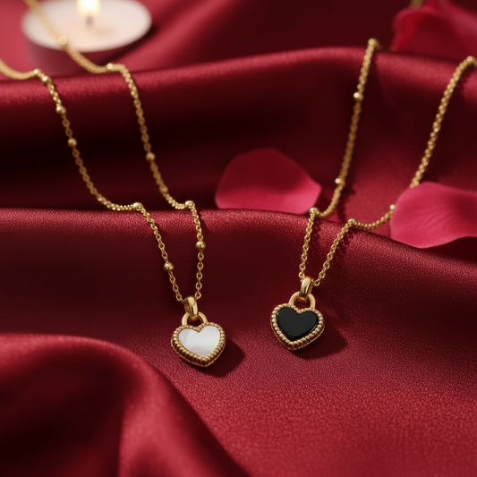 Black/White Reversible Gold Heart Necklace with heart-shaped pendants on a red fabric background