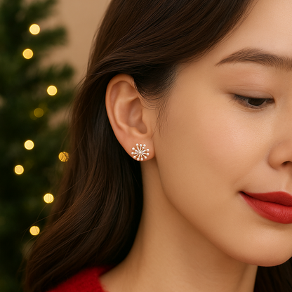 Close-up of a woman wearing Gold Burst Pearl Earrings with a blurred Christmas tree in the background