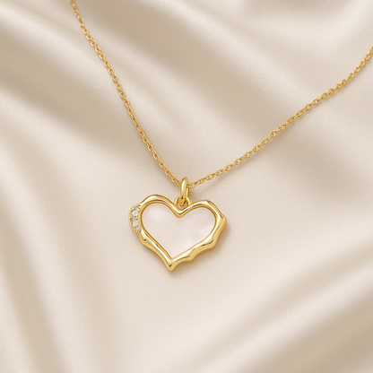 Gold Heart Mother of Pearl Necklace with small diamonds on a beige fabric background