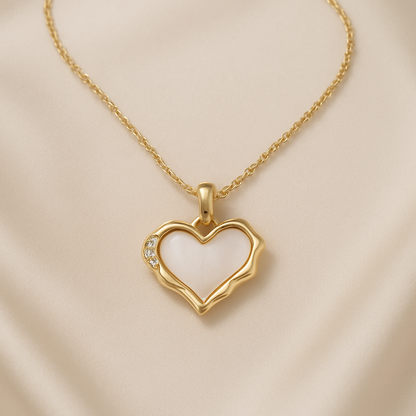 Gold Heart Mother of Pearl Necklace with small diamonds on a white and beige fabric background