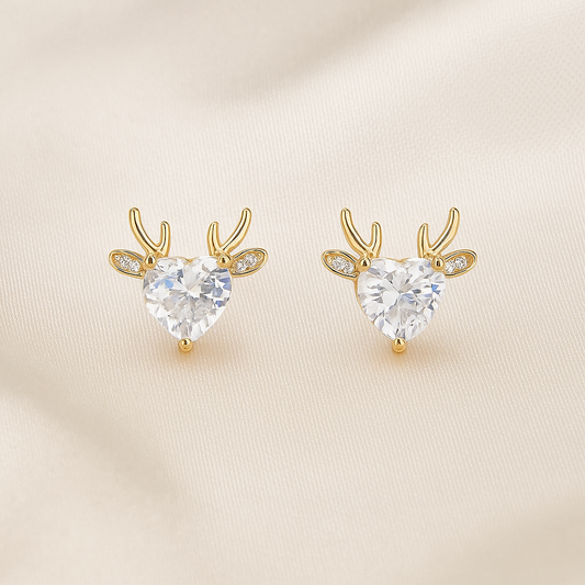 Gold Reindeer Zircon Heart Earrings with clear heart-shaped gemstones on a beige background