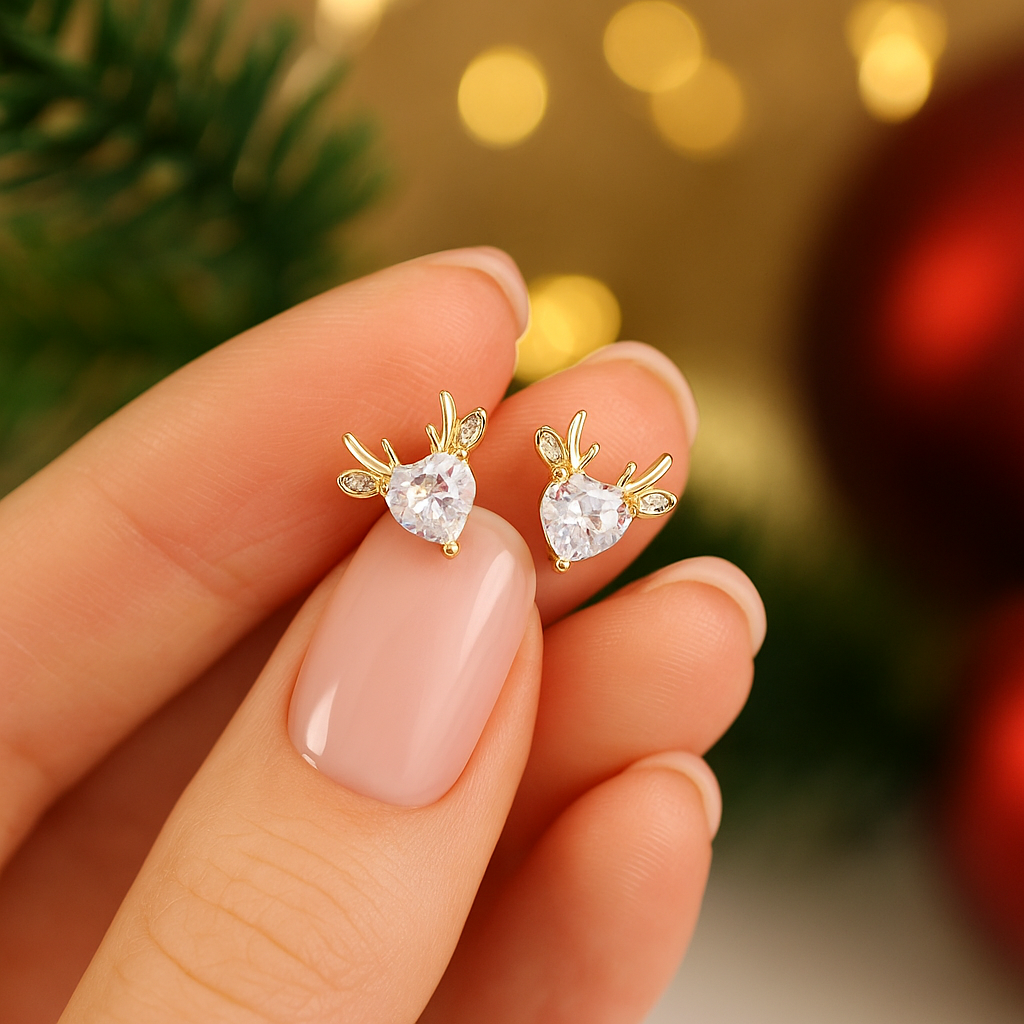 Gold Reindeer Zircon Heart Earrings held between fingers with a festive background