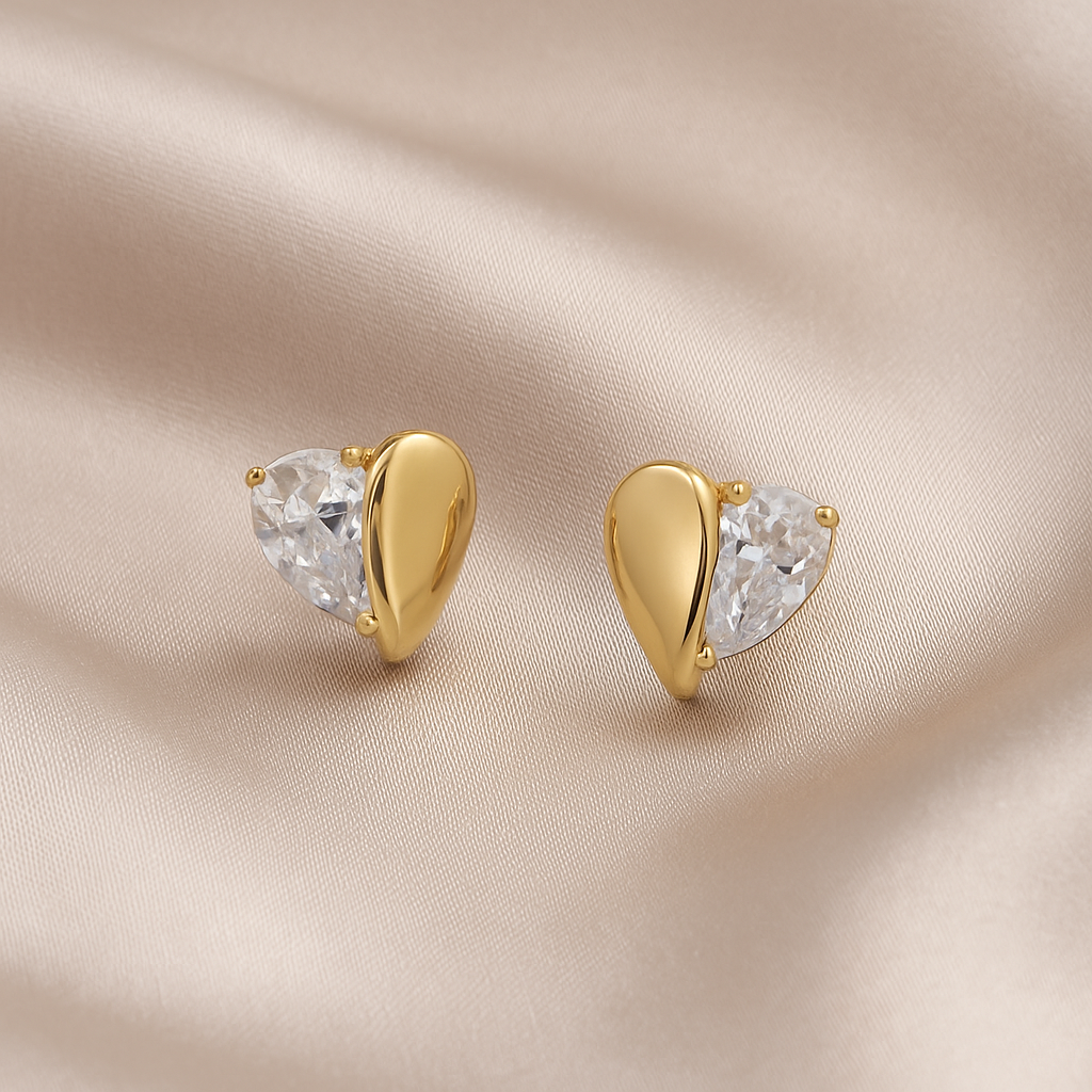 Gold Zircon Heart Earrings with clear gemstones on a beige fabric background