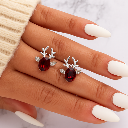Ruby Reindeer Earrings with red gemstones on a hand with white nail polish.