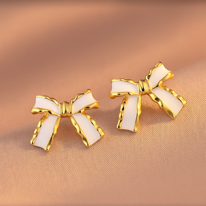 White and Gold Bow Earrings on a beige background