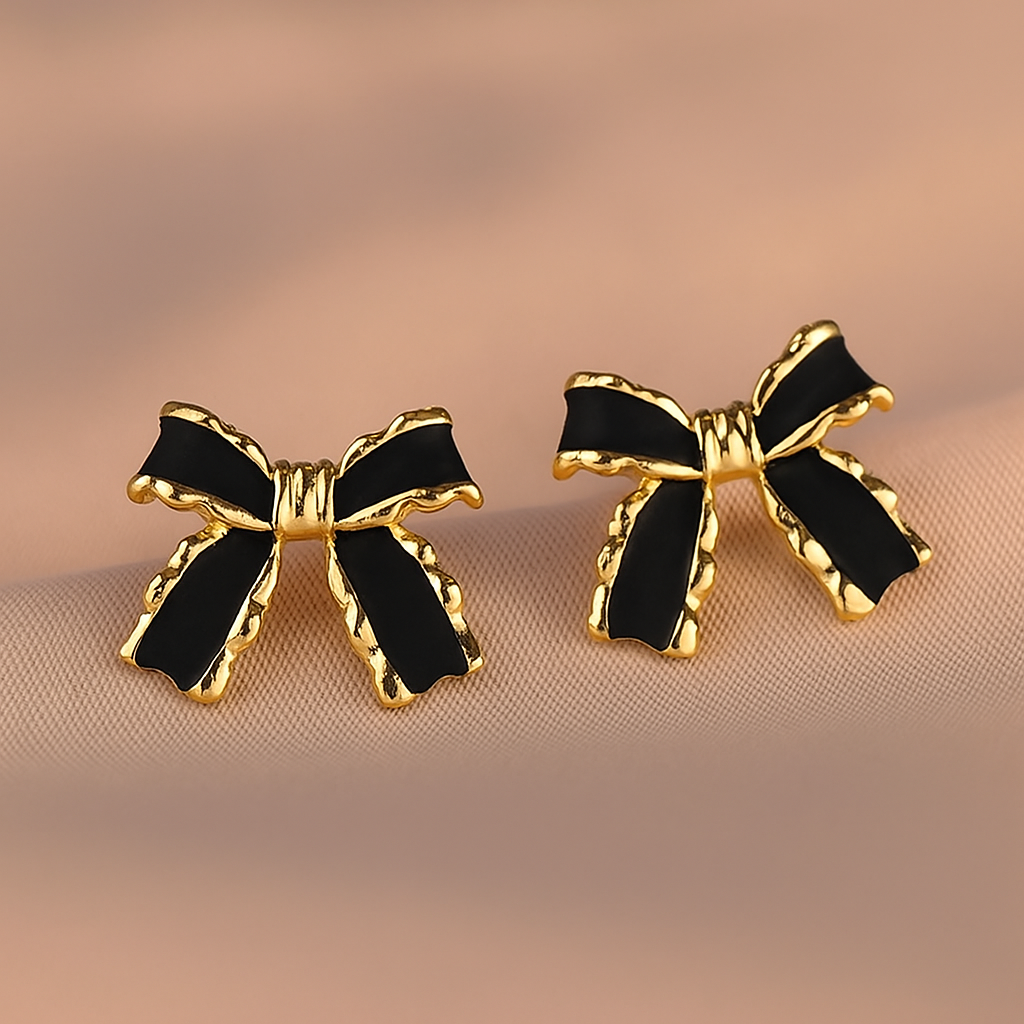 Black and Gold Bow Earrings with black centers on a beige background