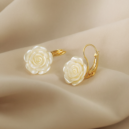 White Rose Earrings with white rose-shaped stones on a beige fabric background