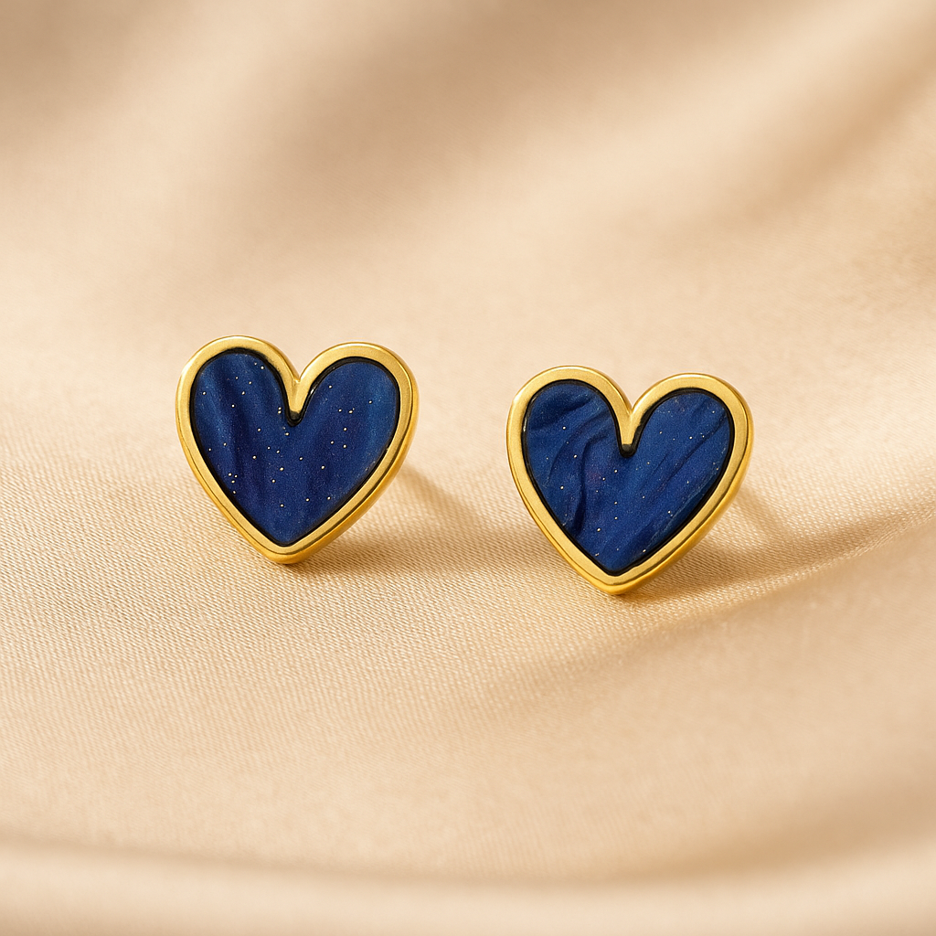Blue Gold Dust Heart Earrings with blue centers and gold borders on a beige fabric background