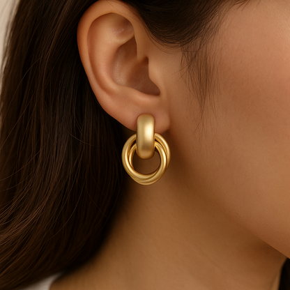 Close-up of a person wearing a satin gold earring with a blurred background