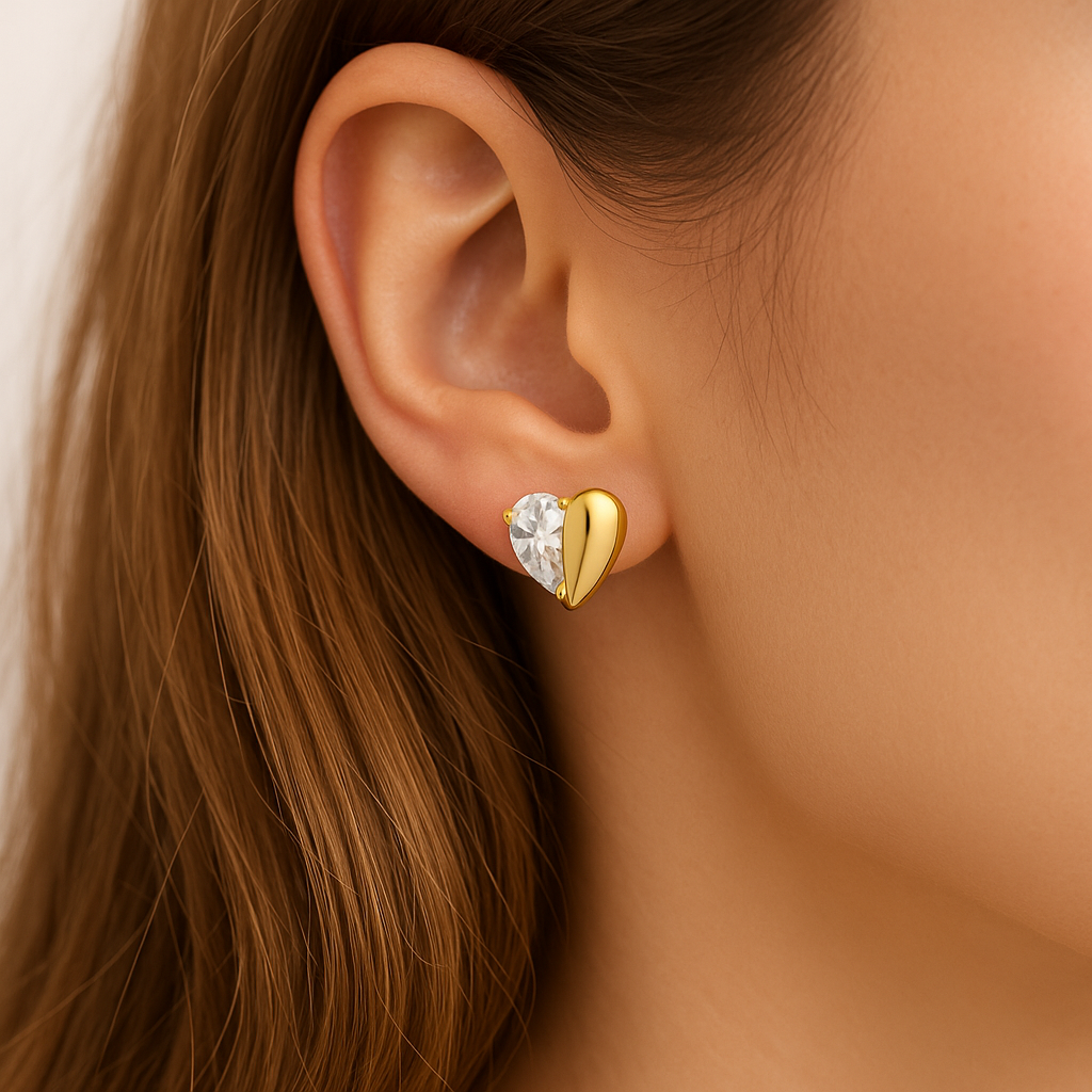 Close-up of a woman wearing a Gold Zircon Heart Earring with a clear gemstone.