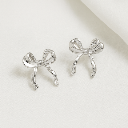Silver Bow Ribbon Earrings on a light beige background