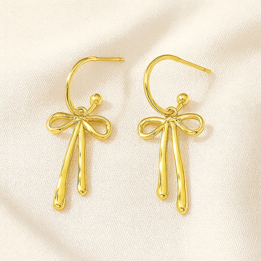 Gold Ribbon Dangle Earrings on a light beige fabric background