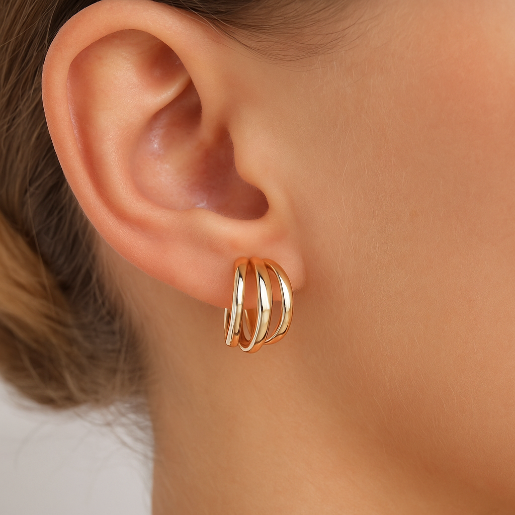 Gold hoop earrings worn by a person with a neutral background