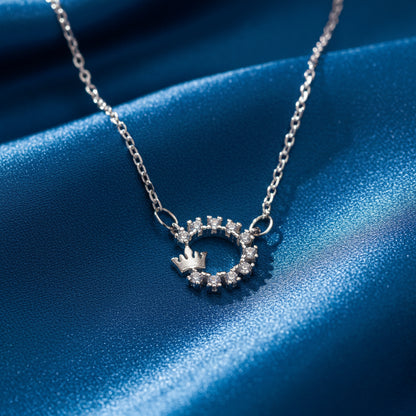 Silver Crowned Crystal Halo Necklace with a circular pendant on a blue fabric background