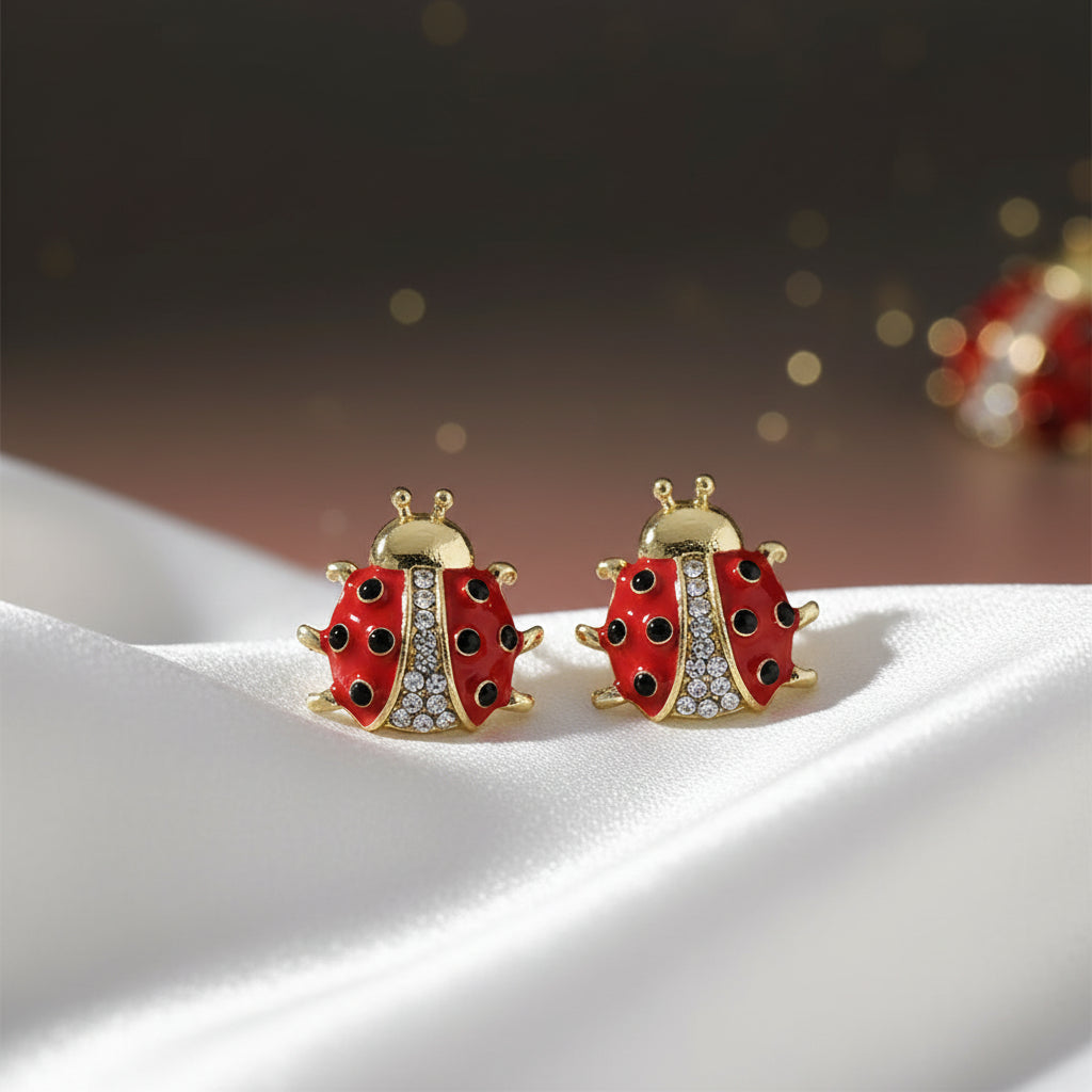 Crystal Accent Ladybug Earrings with gold accents on a white textured surface