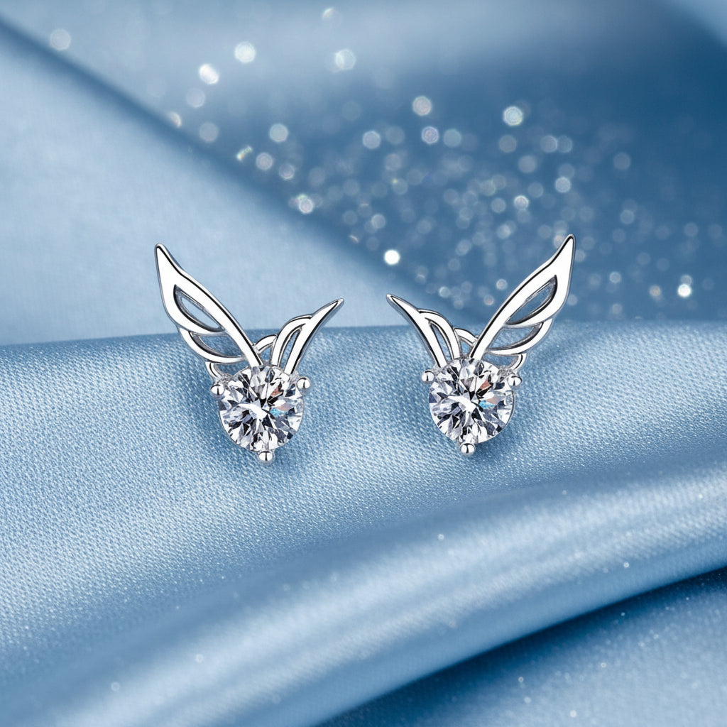Crystal Angel Wing Stud Earrings with diamond-like stones on a blue textured background