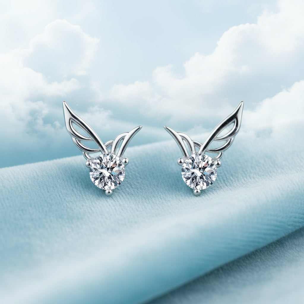 Silver Crystal Angel Wing Stud Earrings with diamond-like stones on a blue textured background