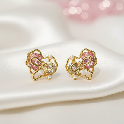 Crystal Bow Heart Earrings with pink gemstones and pearl accents on a beige background
