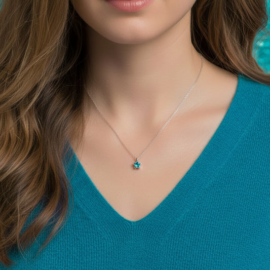 Dainty Silver Blue Star Necklace with blue gem on a light gray background