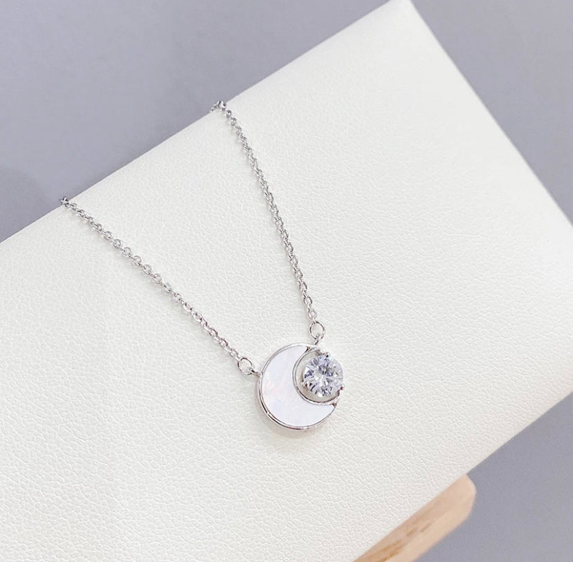 Crystal Crescent Moon Necklace with a moon and star pendant on a white surface