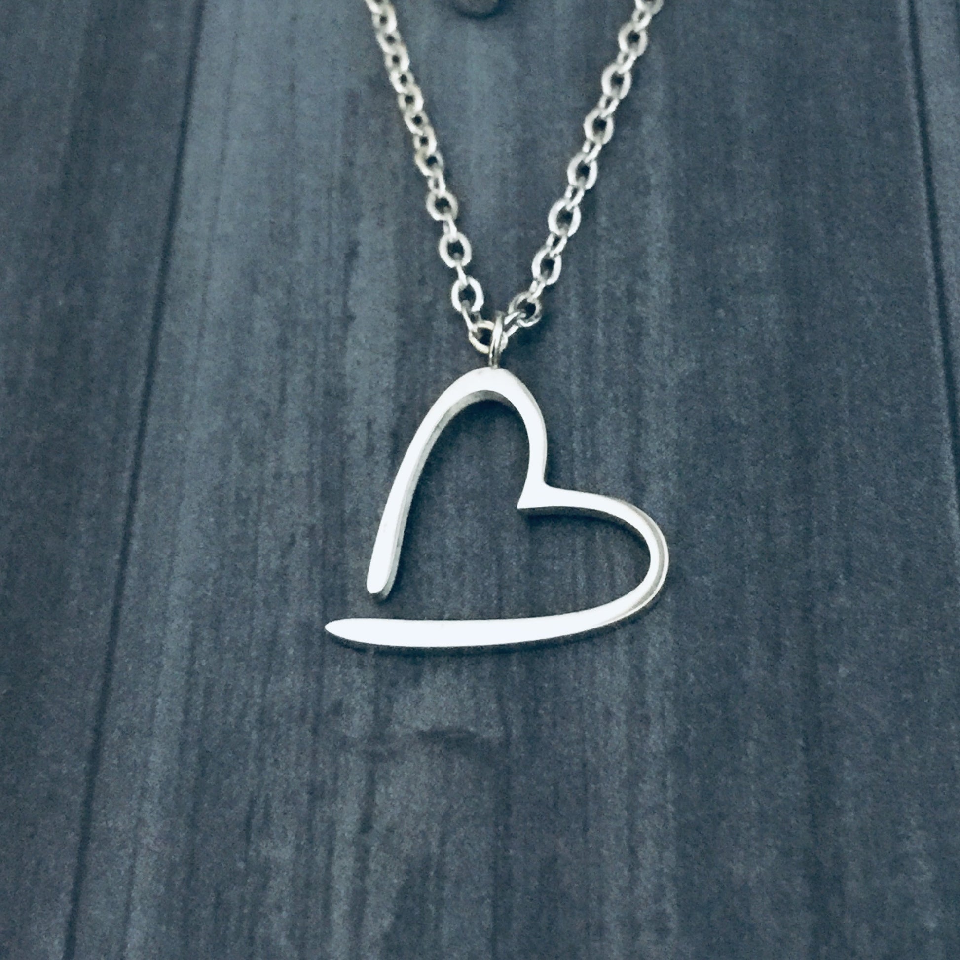 Silver Floating Heart Necklace against a dark wooden background