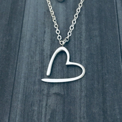 Silver Floating Heart Necklace against a dark wooden background